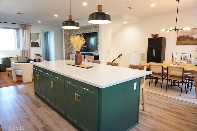 kitchen featuring hanging light fixtures, light hardwood / wood-style flooring, a center island, and green cabinets