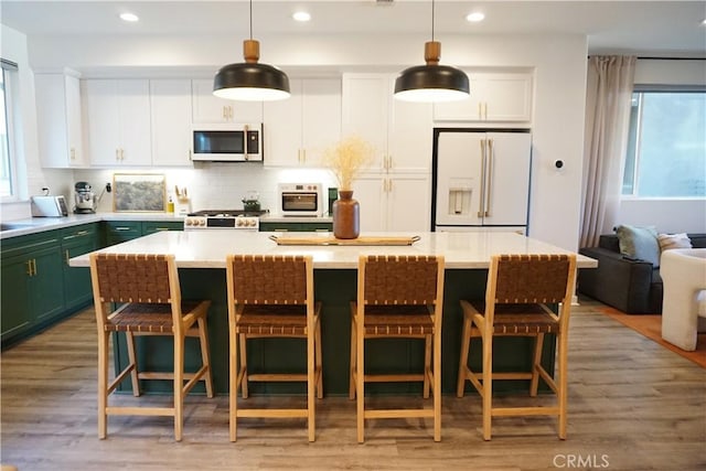 kitchen with white appliances, decorative light fixtures, a center island, and a kitchen bar