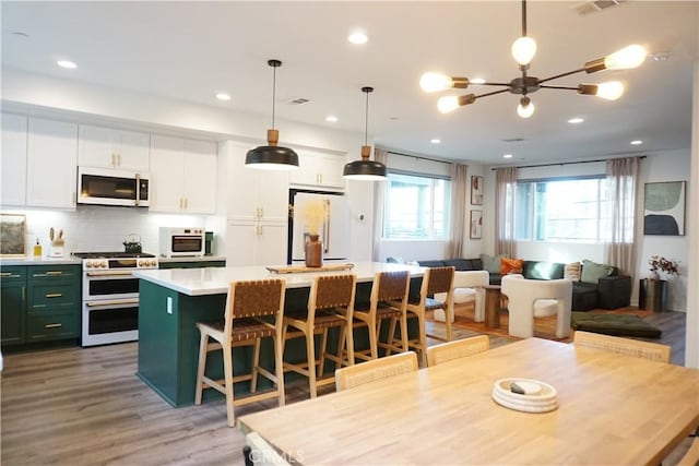 kitchen with a breakfast bar, pendant lighting, decorative backsplash, a center island, and white appliances