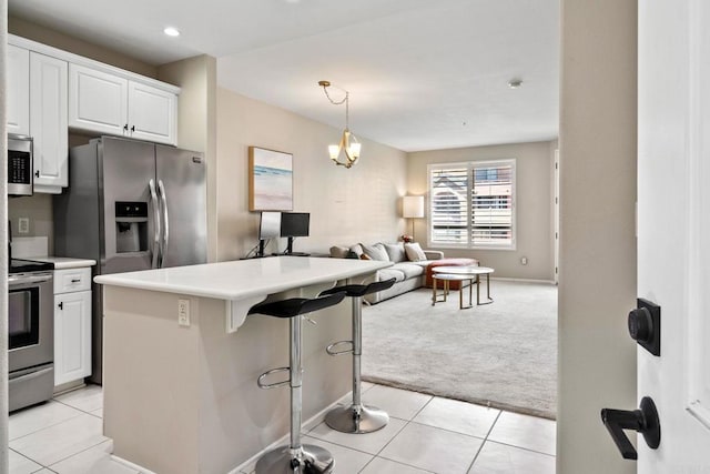 kitchen featuring light carpet, a kitchen bar, stainless steel appliances, a kitchen island, and white cabinets