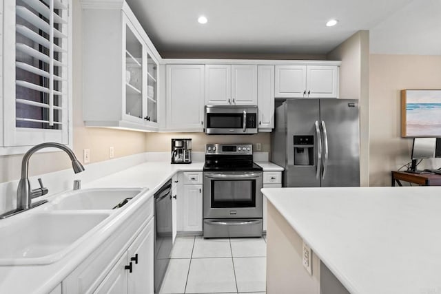 kitchen with light tile patterned floors, sink, white cabinets, and appliances with stainless steel finishes