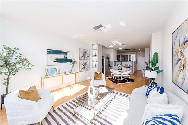 living area featuring light wood-style flooring and visible vents