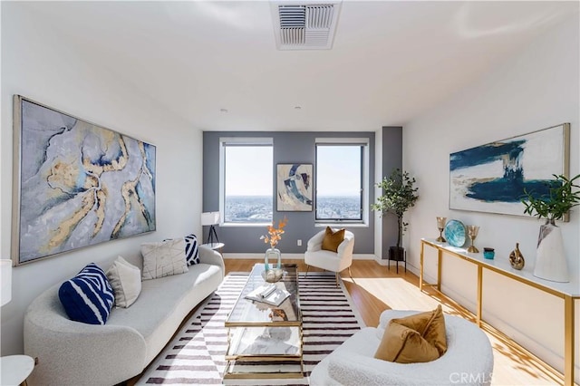 living area with wood finished floors, visible vents, and baseboards