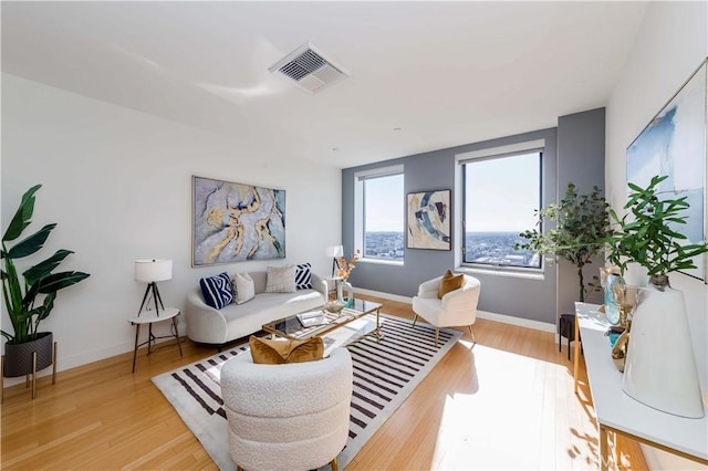 living room featuring light wood-style flooring, visible vents, and baseboards