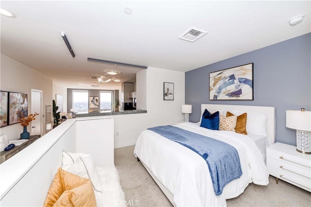 bedroom with baseboards, visible vents, and light colored carpet