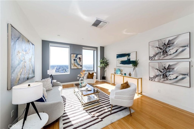 living room featuring visible vents, baseboards, and wood finished floors