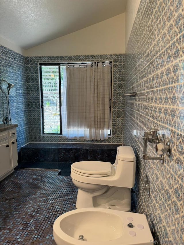 bathroom featuring vaulted ceiling, tile walls, toilet, a bidet, and tile patterned floors