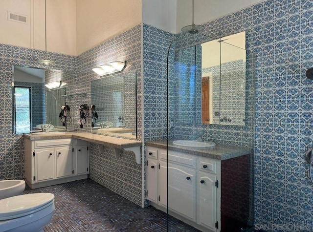 bathroom with tile patterned floors, toilet, tile walls, a bidet, and vanity