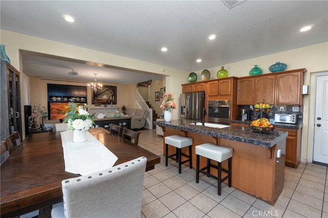 kitchen with an inviting chandelier, a breakfast bar area, appliances with stainless steel finishes, backsplash, and hanging light fixtures