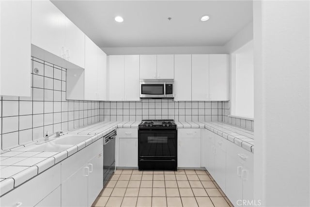 kitchen with tasteful backsplash, white cabinetry, light tile patterned floors, tile counters, and black appliances