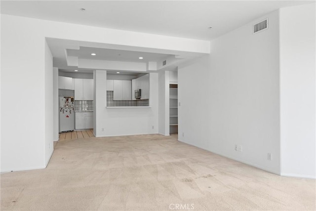 unfurnished living room with light colored carpet