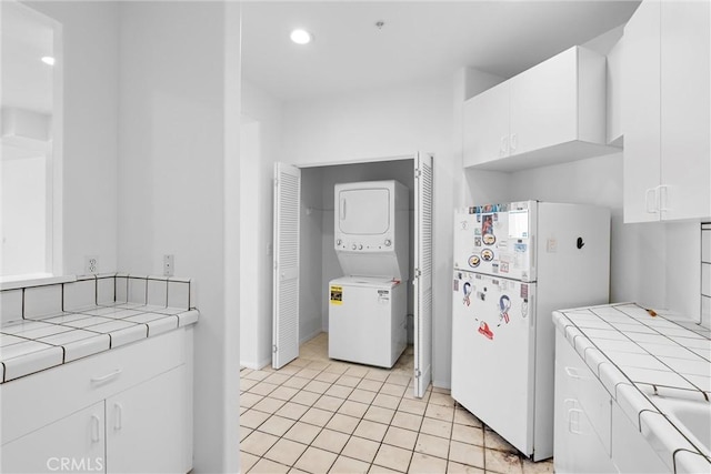 kitchen with stacked washer and dryer, tile countertops, white cabinets, and white fridge