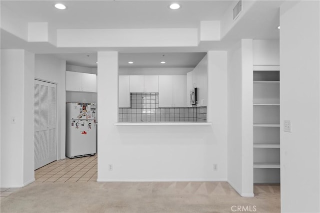 kitchen featuring white refrigerator, white cabinetry, light colored carpet, and tasteful backsplash