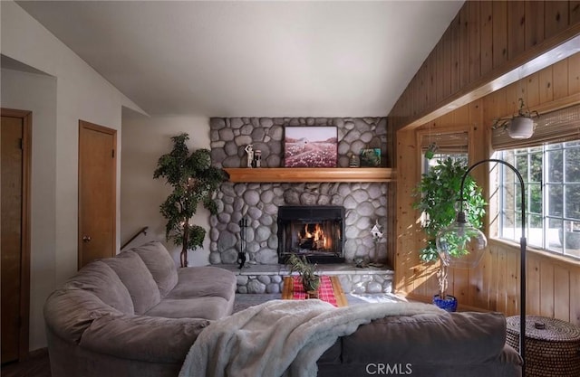 living room with vaulted ceiling, a fireplace, and wooden walls