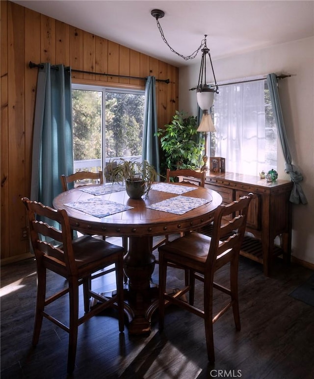 dining space featuring dark hardwood / wood-style flooring and wood walls