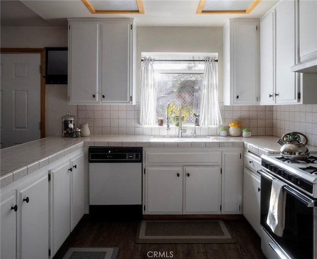 kitchen with dark hardwood / wood-style floors, tile countertops, decorative backsplash, white appliances, and white cabinets