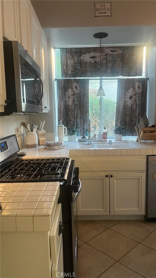 kitchen featuring light tile patterned floors, appliances with stainless steel finishes, tile countertops, and white cabinets