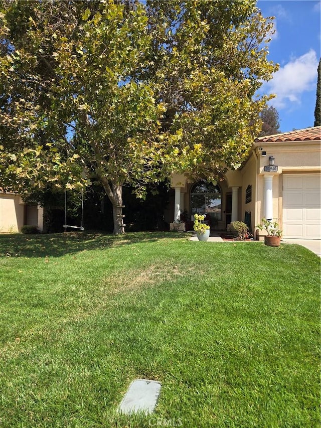 view of property hidden behind natural elements with a garage and a front yard