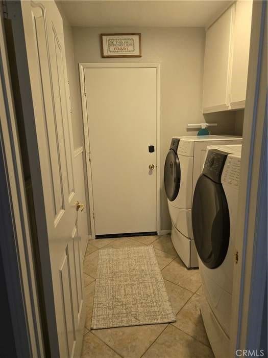 clothes washing area with light tile patterned floors, cabinets, and washer and clothes dryer