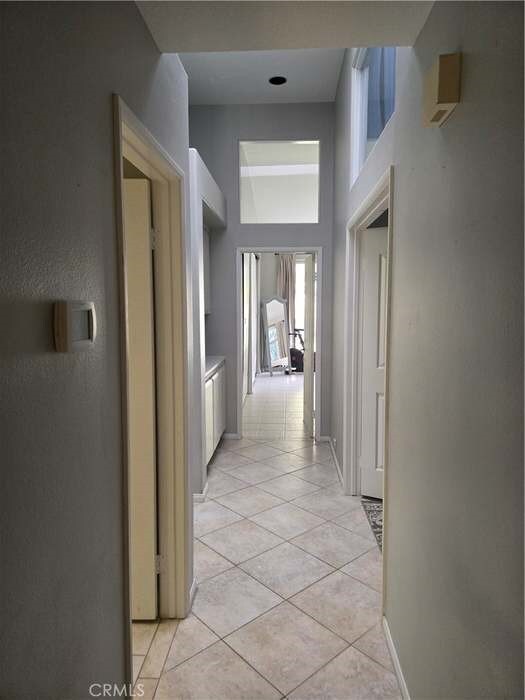 hall featuring a towering ceiling and light tile patterned flooring