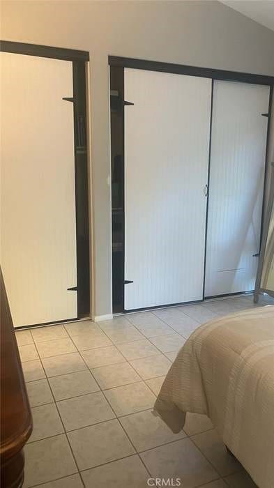 unfurnished bedroom featuring light tile patterned floors, a closet, and vaulted ceiling