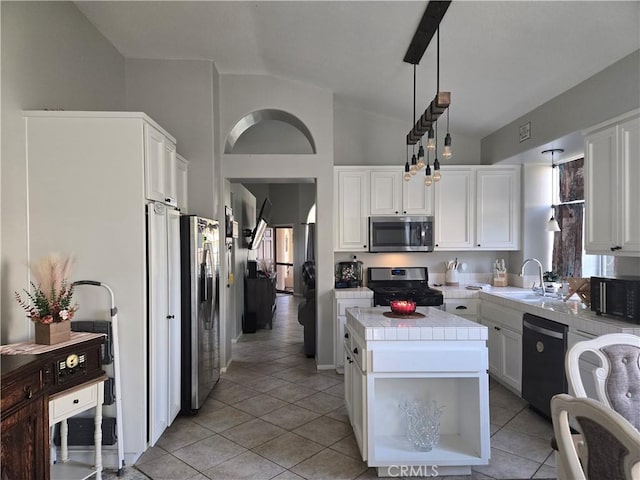 kitchen featuring black appliances, lofted ceiling, tile counters, decorative light fixtures, and white cabinetry