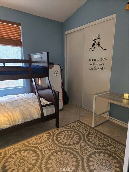 bedroom with tile patterned flooring, vaulted ceiling, and a closet