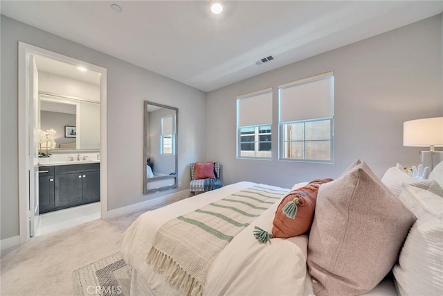 bedroom featuring ensuite bathroom, sink, and light colored carpet