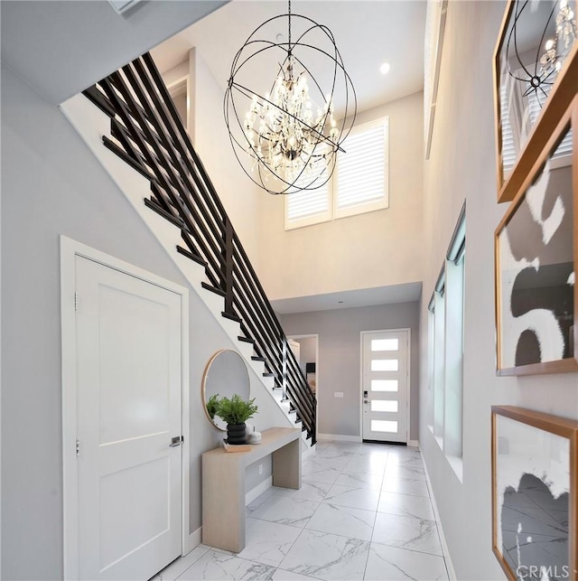 foyer entrance featuring a wealth of natural light, a chandelier, and a high ceiling