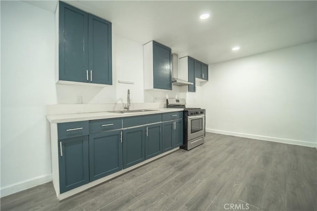 kitchen featuring sink, hardwood / wood-style floors, stainless steel gas range, and wall chimney exhaust hood