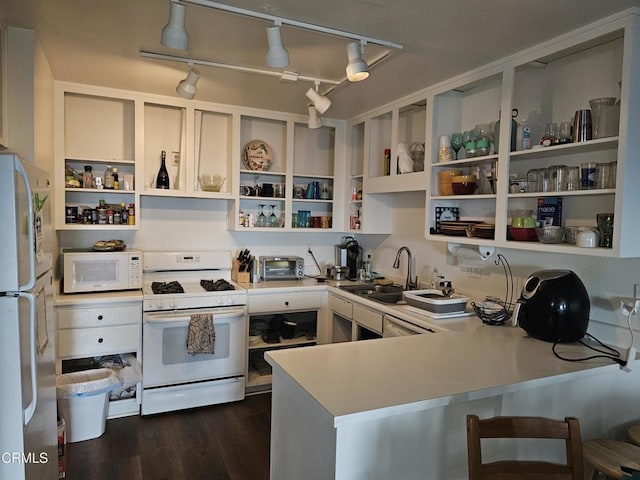 kitchen featuring white appliances, sink, track lighting, kitchen peninsula, and dark hardwood / wood-style floors