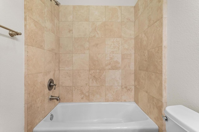 bathroom featuring tiled shower / bath and toilet