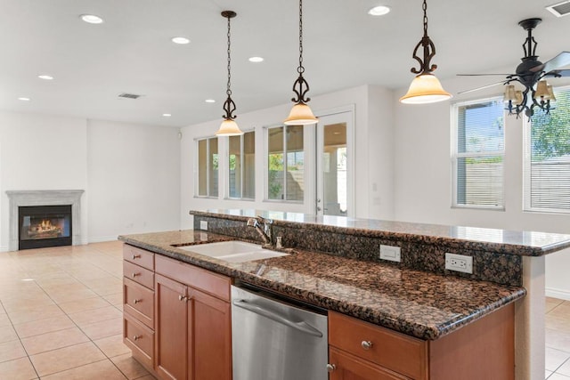 kitchen featuring pendant lighting, stainless steel dishwasher, sink, and a center island with sink