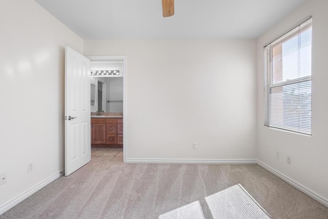 unfurnished bedroom featuring ceiling fan, ensuite bathroom, sink, and light carpet