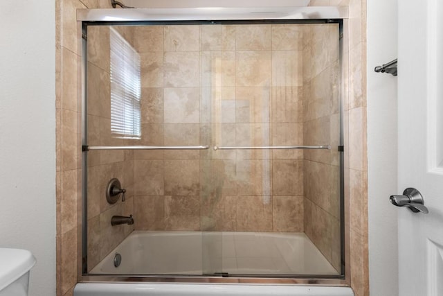 bathroom featuring bath / shower combo with glass door and toilet