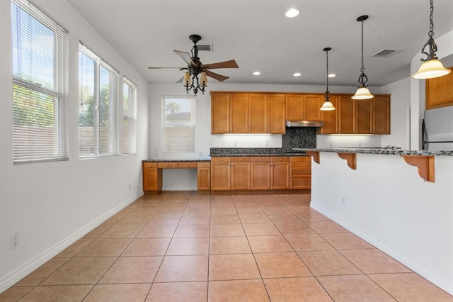 kitchen with pendant lighting, ceiling fan, a kitchen breakfast bar, and light tile patterned flooring