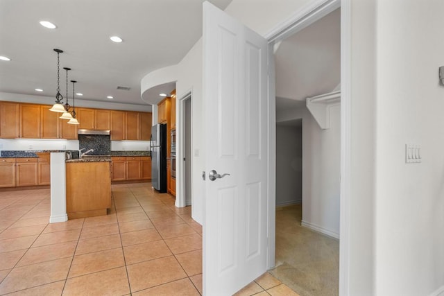 kitchen featuring pendant lighting, light tile patterned floors, a breakfast bar area, stainless steel refrigerator, and a center island