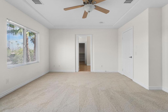 unfurnished bedroom featuring a spacious closet, light colored carpet, ceiling fan, and a closet