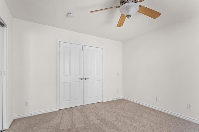 unfurnished bedroom featuring ceiling fan, light colored carpet, and a closet