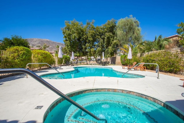 view of pool featuring a mountain view, a patio area, and an in ground hot tub