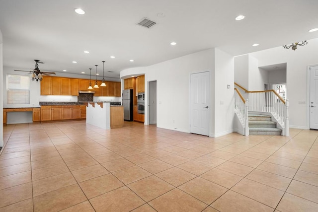 kitchen featuring light tile patterned flooring, a center island, hanging light fixtures, appliances with stainless steel finishes, and ceiling fan