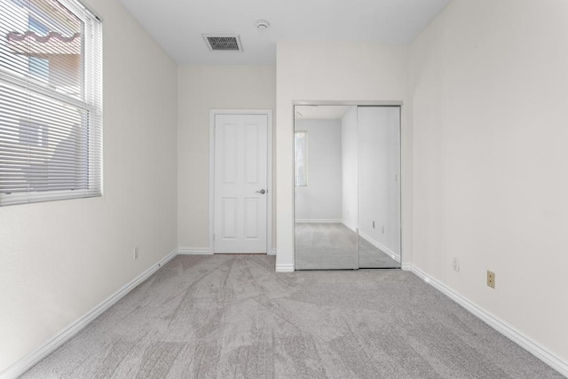 unfurnished bedroom featuring light colored carpet and a closet