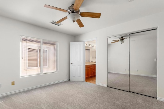 unfurnished bedroom featuring ceiling fan, connected bathroom, light carpet, and a closet