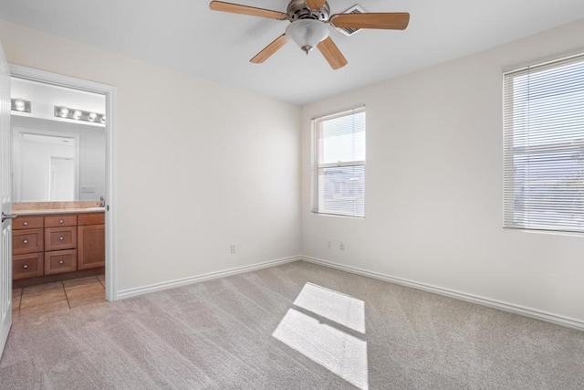 unfurnished bedroom featuring light carpet, connected bathroom, and ceiling fan