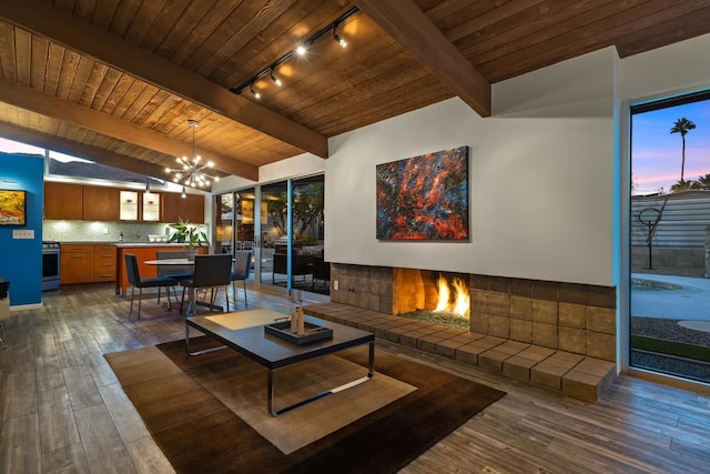 living room featuring vaulted ceiling with beams, dark wood-type flooring, track lighting, a chandelier, and wooden ceiling