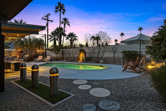 pool at dusk featuring a patio area