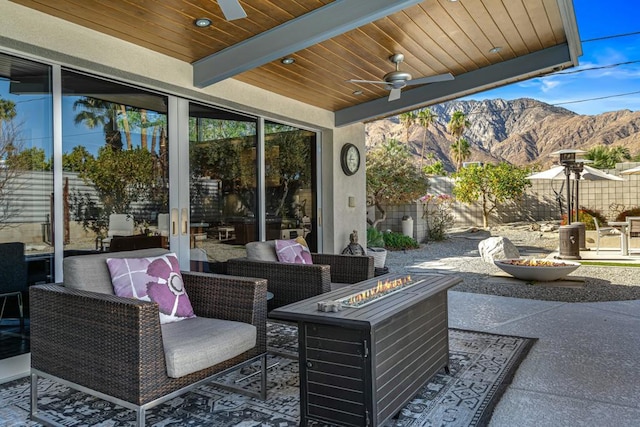 view of patio featuring a mountain view, ceiling fan, and an outdoor living space with a fire pit