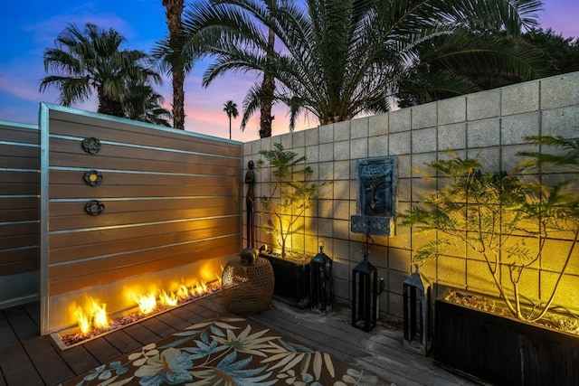 deck at dusk featuring a fireplace