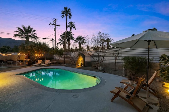 pool at dusk with a patio area