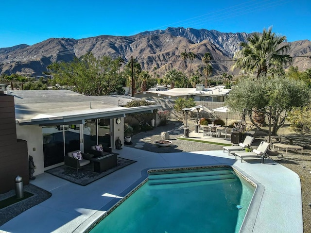 view of swimming pool featuring a mountain view, a patio area, and an outdoor fire pit